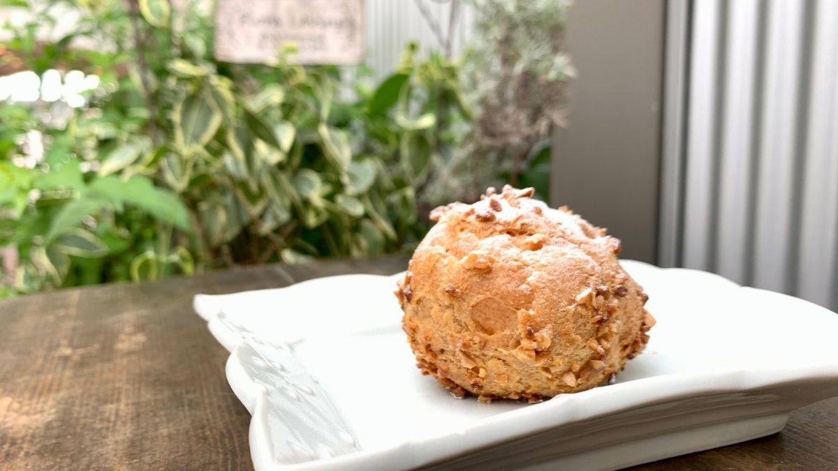 プチ・ラパンのシュークリーム。板の上に乗った四角い皿に乗っている。奥には緑の植木が見える。